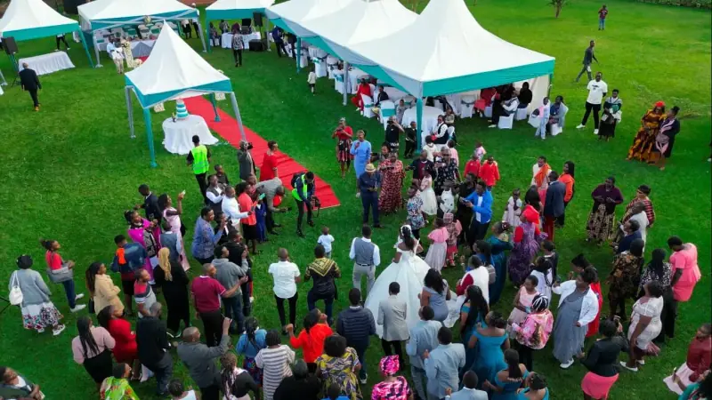 Wide view of a garden wedding reception with white tents and guests